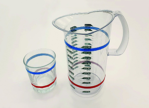 Glas och tillbringare med röd och blå rand, som visar hur mycket saft respektive vatten som ska fyllas i.